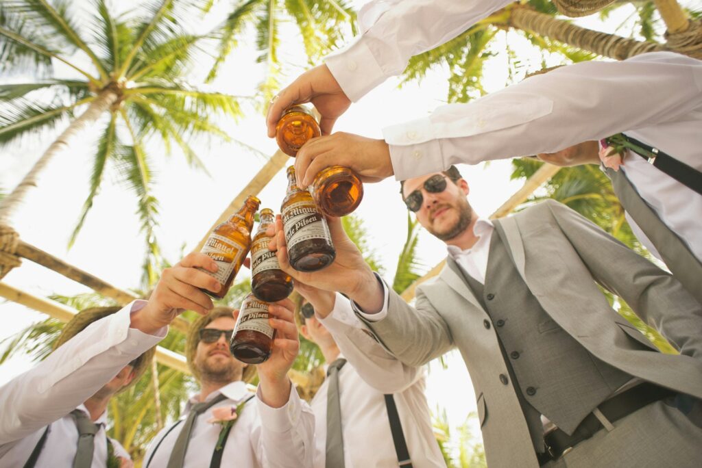 low angle of men holding beer bottles and having a toast bachelor party